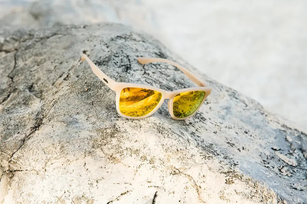 Polarised sunglasses with yellow mirrored lenses on a textured rock outdoors