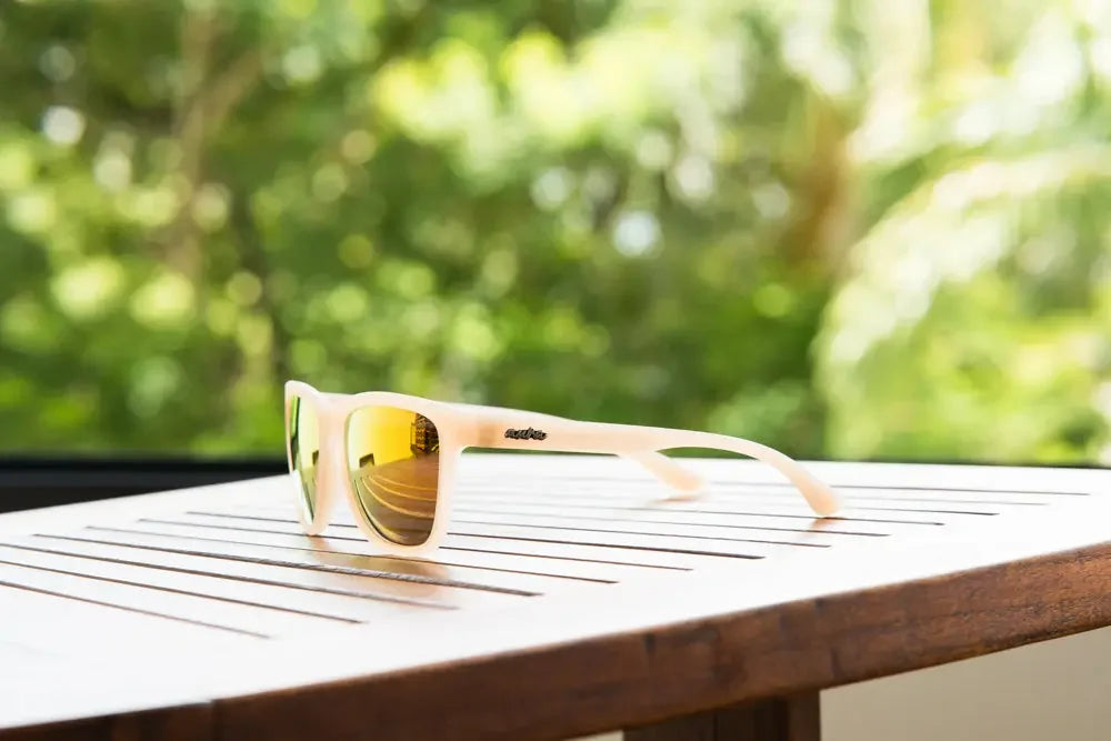Polarized sunglasses with yellow mirrored lenses on a wooden table outdoors