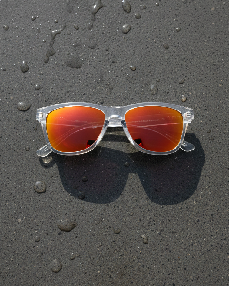 Sunglasses with red reflective lenses on a wet black surface
