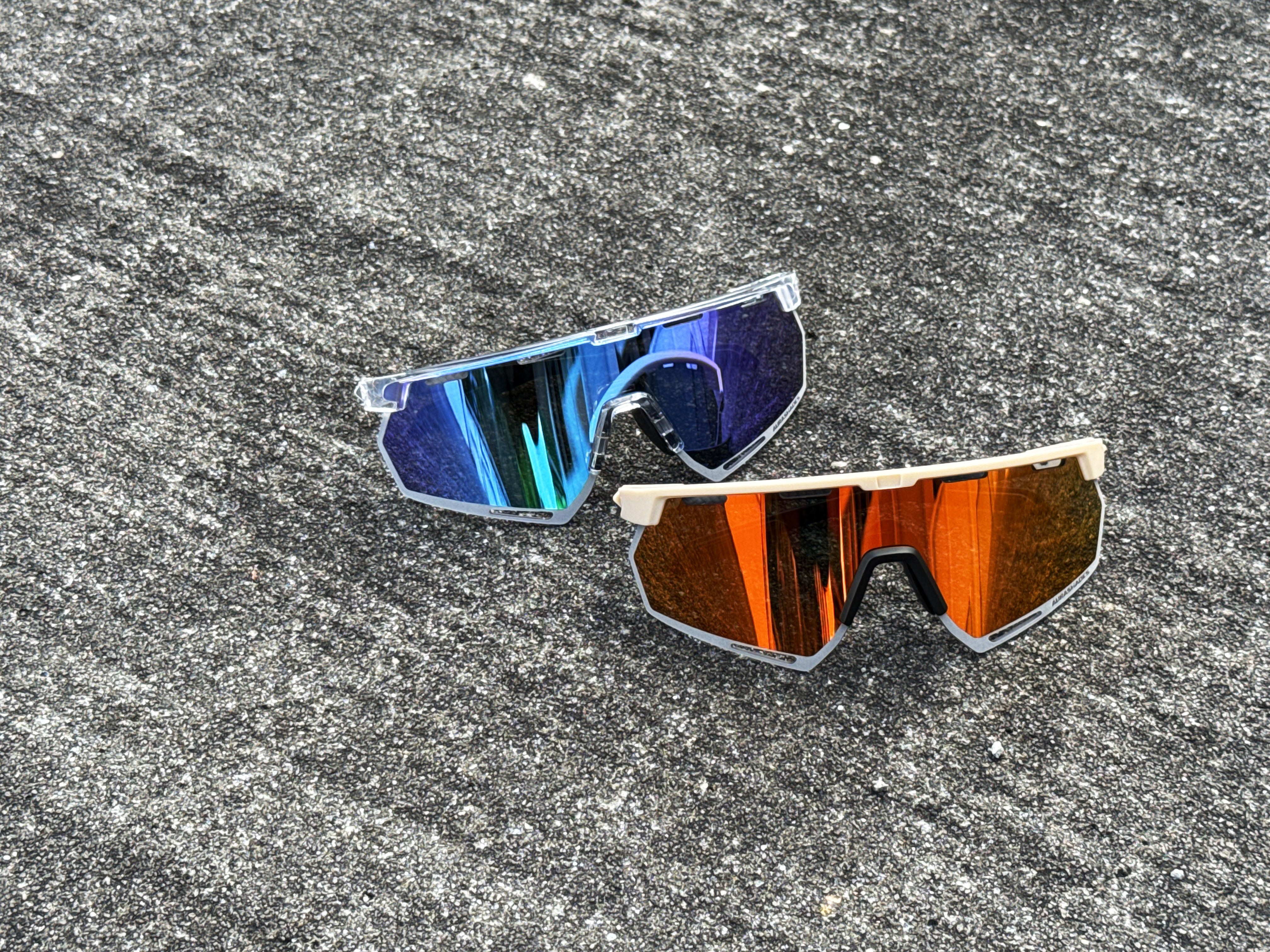 Polarised sunglasses with blue and orange mirrored lenses on textured outdoor surface